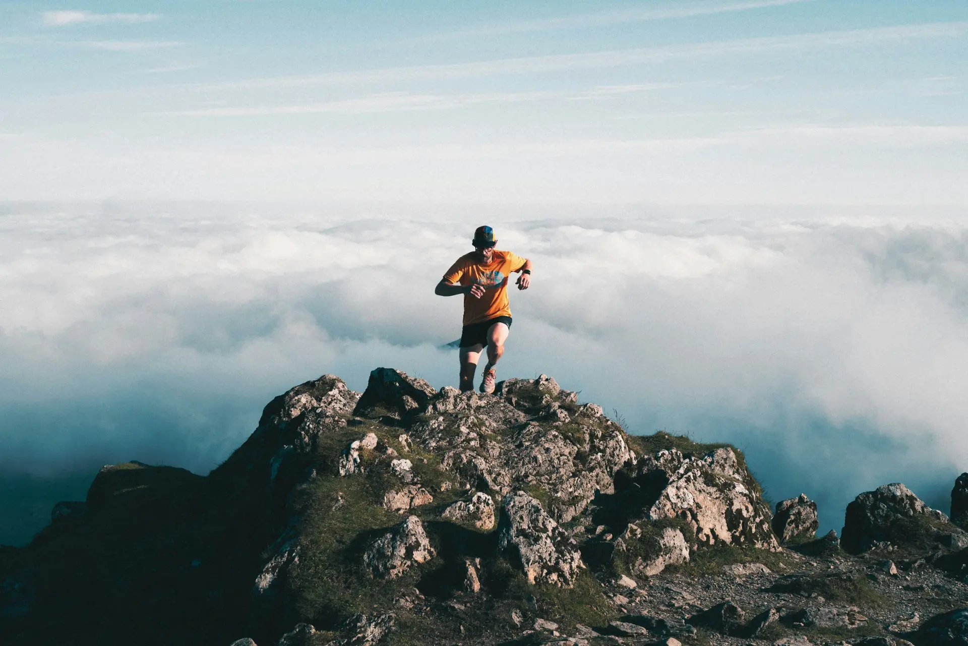 Coureur en montagne au sommet d'un rocher, au-dessus des nuages